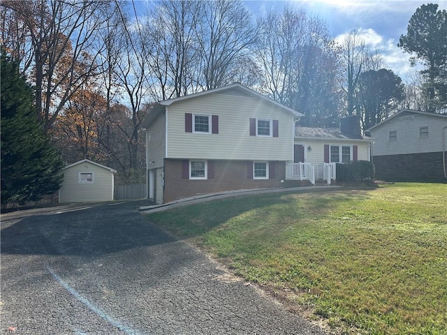 split level home featuring a front yard, a garage, and a storage shed