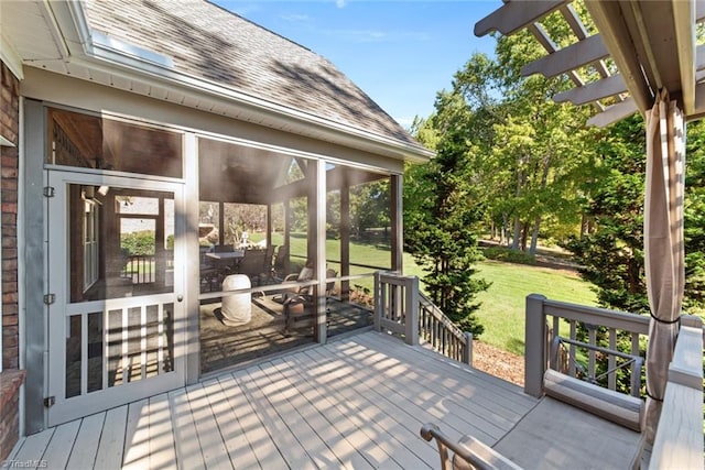 wooden terrace featuring a sunroom and a lawn