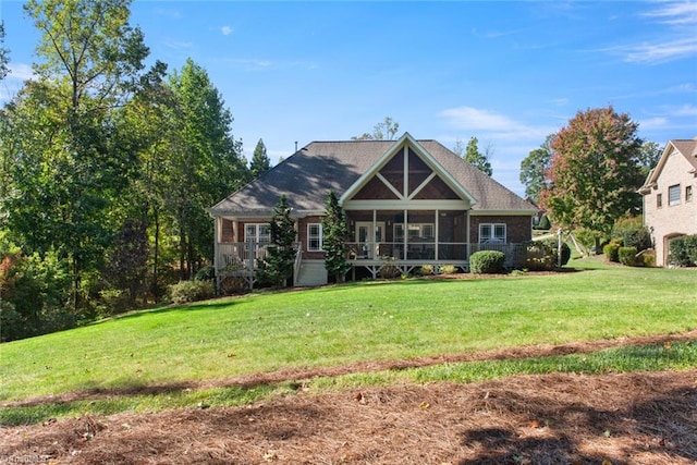 rear view of property featuring a sunroom and a lawn