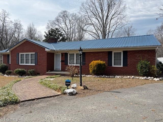 ranch-style house with crawl space, metal roof, and brick siding