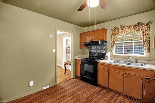 904 Ashe St, Greensboro, NC 27406 - kitchen featuring black / electric stove, exhaust hood, wood finished floors, light countertops, and brown cabinetry