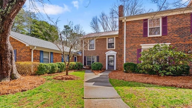 view of front of house with a chimney and brick siding