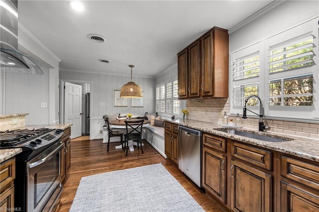 1603 Ilchester Ct, Greensboro, NC 27408 - kitchen with stainless steel appliances, wall chimney exhaust hood, backsplash, light stone counters, and dark wood-style flooring
