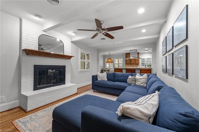 1603 Ilchester Ct, Greensboro, NC 27408 - living area featuring wood finished floors, beamed ceiling, ceiling fan, and a brick fireplace