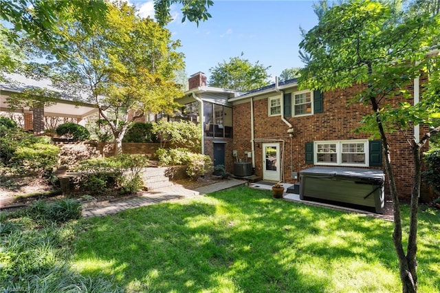 1603 Ilchester Ct, Greensboro, NC 27408 - rear view of house featuring a hot tub, a lawn, brick siding, and a chimney