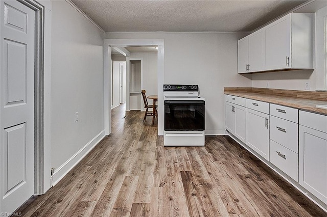 kitchen featuring a textured ceiling, wood finished floors, baseboards, white cabinets, and electric stove