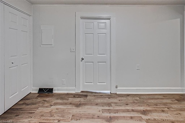 empty room with ornamental molding, visible vents, baseboards, and wood finished floors