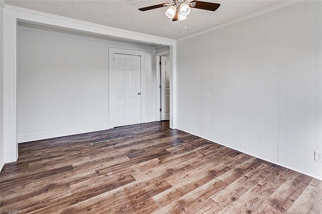 spare room featuring a textured ceiling, ceiling fan, wood finished floors, and crown molding