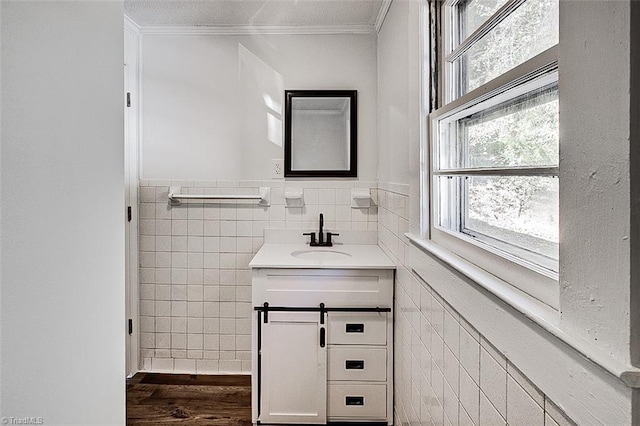 bathroom with a wainscoted wall, tile walls, ornamental molding, vanity, and wood finished floors