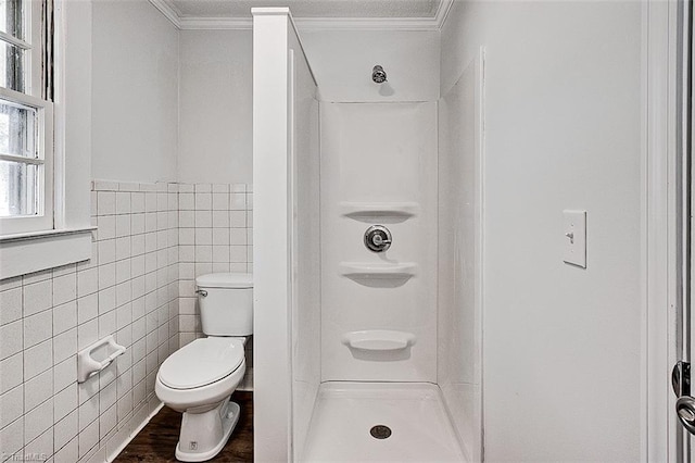 full bathroom with toilet, ornamental molding, wood finished floors, a shower stall, and tile walls