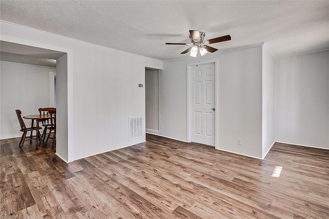 spare room with visible vents, crown molding, a textured ceiling, and wood finished floors