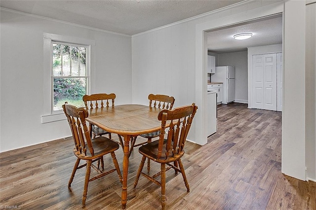 dining area with ornamental molding, a textured ceiling, and wood finished floors