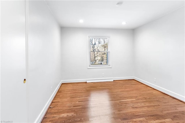 empty room featuring baseboard heating, recessed lighting, wood finished floors, and baseboards