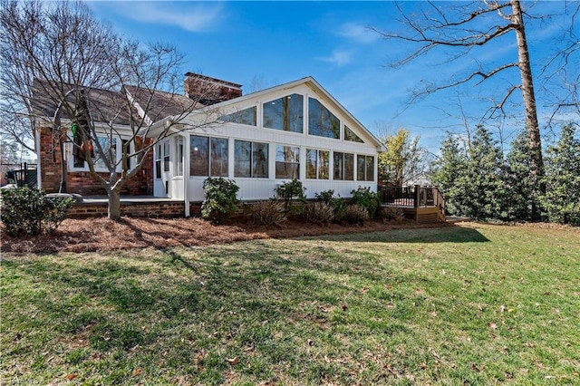 view of front of house featuring a chimney, a front yard, a wooden deck, and a sunroom