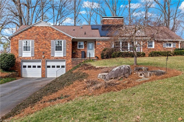 view of front facade featuring brick siding, solar panels, an attached garage, driveway, and a front lawn