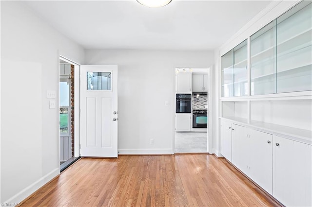 foyer entrance with a healthy amount of sunlight, light wood-style floors, and baseboards