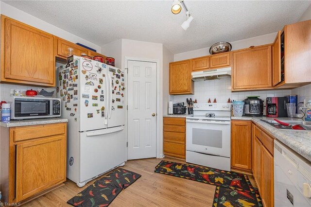 kitchen featuring decorative backsplash, white appliances, a textured ceiling, light hardwood / wood-style flooring, and sink