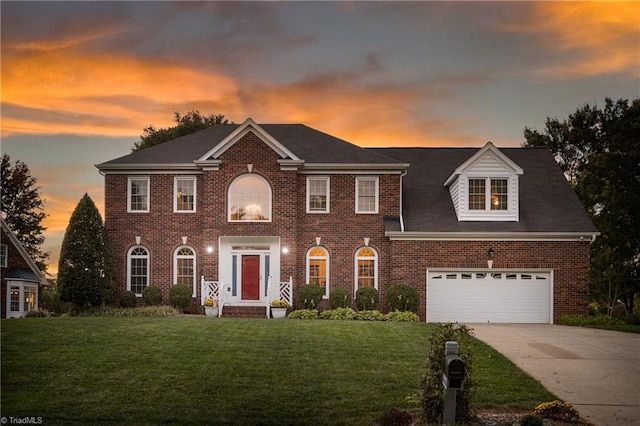 colonial home with a garage and a lawn