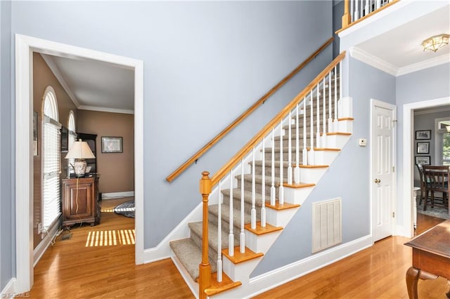 stairway featuring ornamental molding and hardwood / wood-style floors