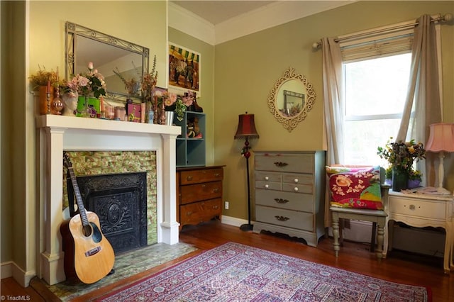 sitting room featuring baseboards, a tile fireplace, crown molding, and wood finished floors