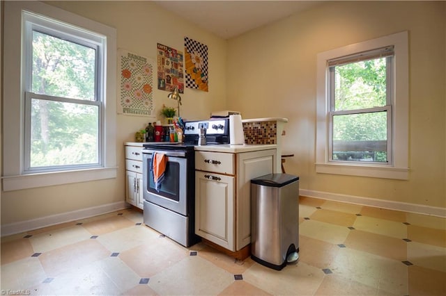kitchen with light countertops, light floors, baseboards, and electric stove