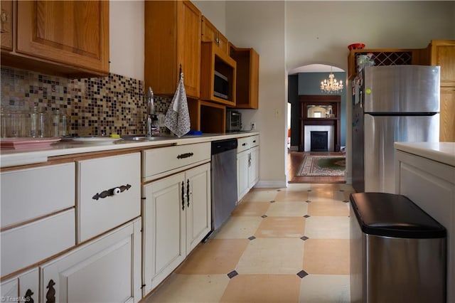 kitchen with light floors, a fireplace, light countertops, decorative backsplash, and appliances with stainless steel finishes