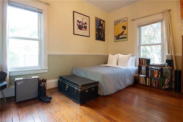 bedroom featuring multiple windows, wainscoting, and wood-type flooring