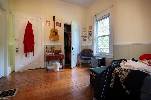 bedroom featuring visible vents, a wainscoted wall, and hardwood / wood-style flooring