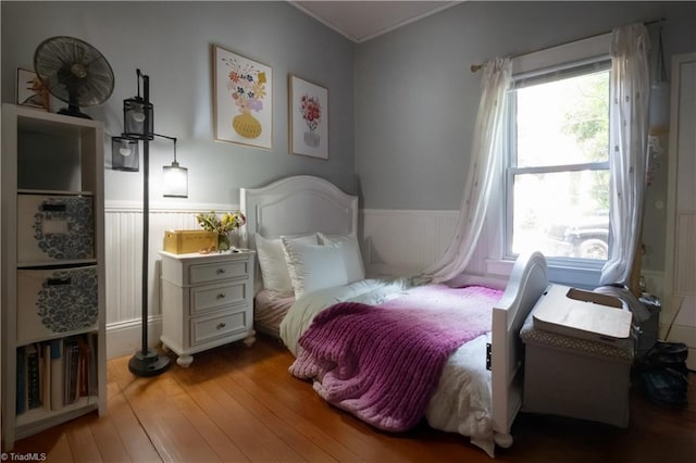 bedroom with a wainscoted wall, crown molding, and hardwood / wood-style flooring