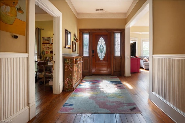 foyer entrance featuring wainscoting, wood-type flooring, and visible vents