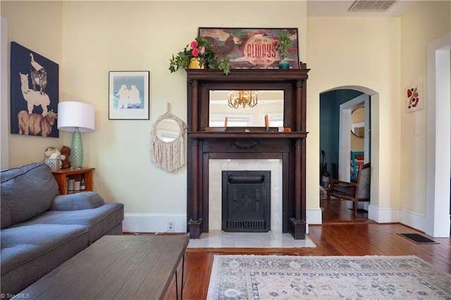 living room with a fireplace with flush hearth, baseboards, hardwood / wood-style floors, and visible vents