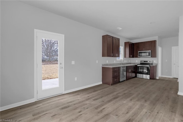 kitchen with dark brown cabinets, sink, stainless steel appliances, and light wood-type flooring