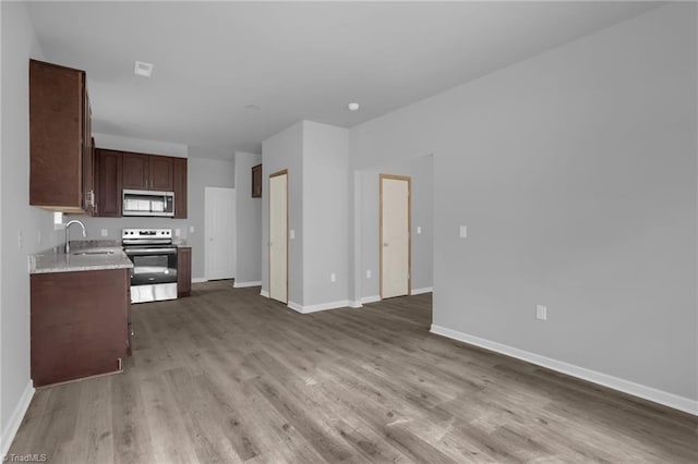 kitchen featuring light wood-type flooring, appliances with stainless steel finishes, dark brown cabinets, and sink