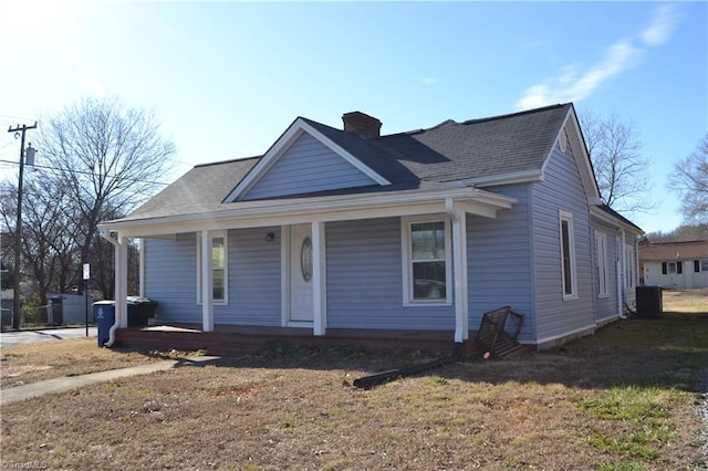 bungalow-style house featuring cooling unit, covered porch, and a front lawn