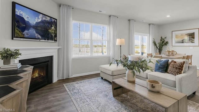 living room featuring a glass covered fireplace, recessed lighting, baseboards, and wood finished floors