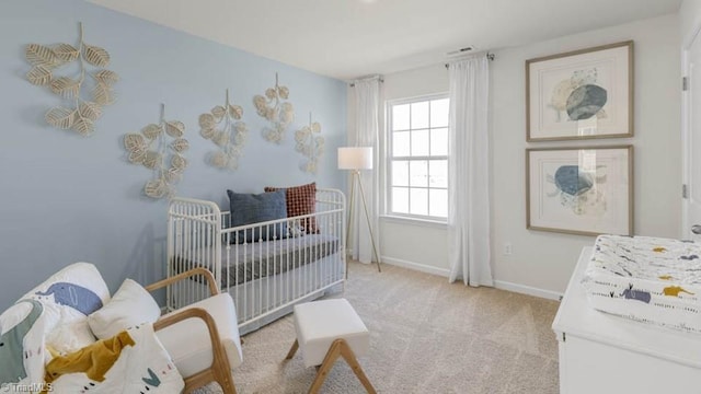 bedroom with a nursery area, light colored carpet, and baseboards