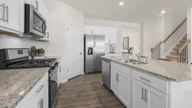 kitchen with dark wood-style floors, a sink, white cabinets, appliances with stainless steel finishes, and backsplash