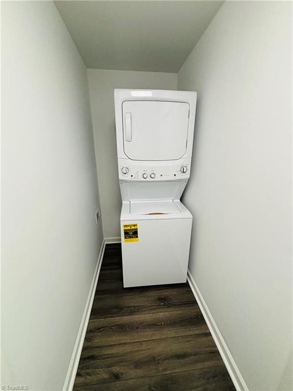 washroom with stacked washer and dryer and dark wood-type flooring