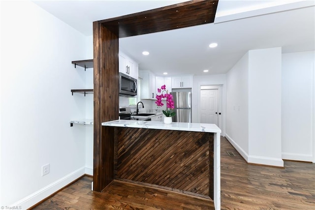 kitchen with sink, stainless steel appliances, kitchen peninsula, and white cabinetry