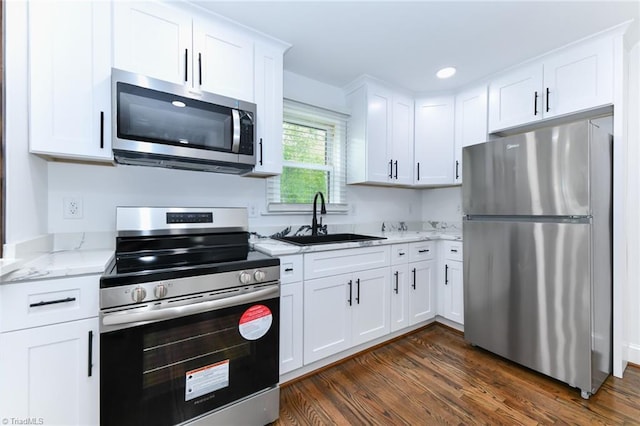 kitchen featuring appliances with stainless steel finishes, light stone counters, dark hardwood / wood-style floors, white cabinets, and sink