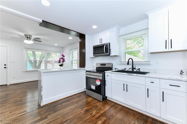 kitchen with kitchen peninsula, dark wood-type flooring, white cabinets, appliances with stainless steel finishes, and sink