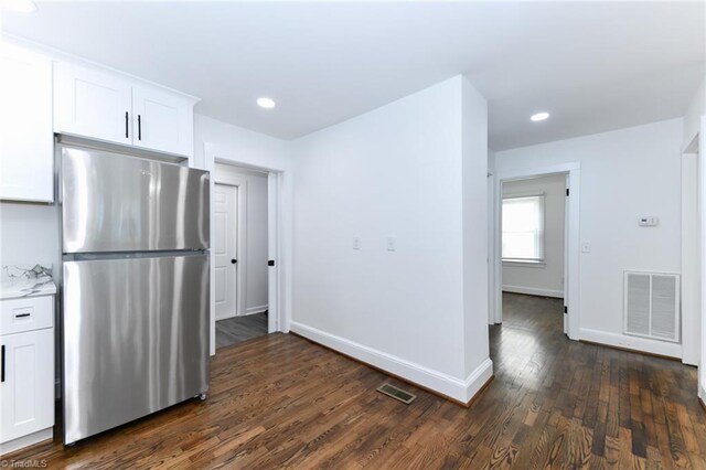 kitchen featuring light stone counters, stainless steel fridge, dark hardwood / wood-style floors, and white cabinetry