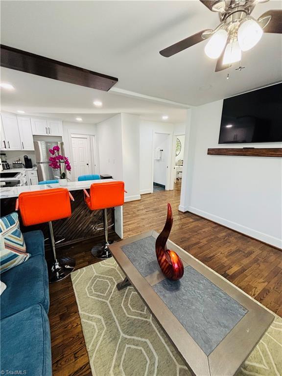 living room with ceiling fan and dark wood-type flooring