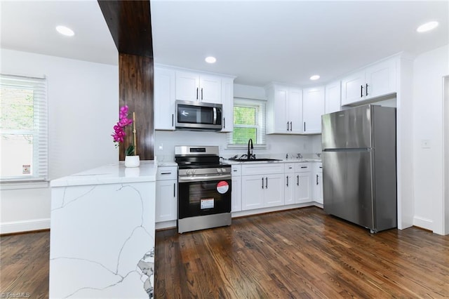 kitchen with light stone countertops, white cabinets, dark wood-type flooring, and appliances with stainless steel finishes