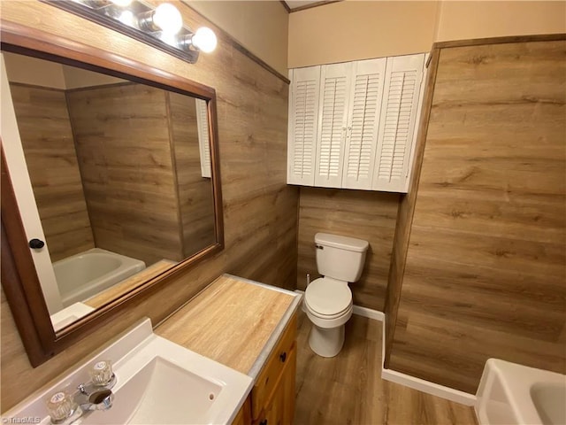 bathroom with a bath, hardwood / wood-style floors, wood walls, and toilet