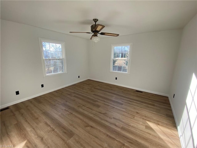 spare room with hardwood / wood-style flooring, ceiling fan, and a healthy amount of sunlight