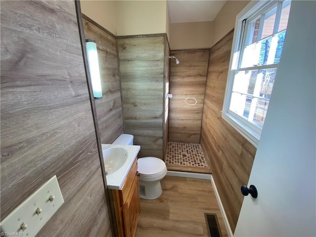 bathroom featuring vanity, toilet, wood-type flooring, and a tile shower