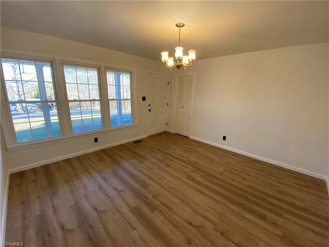 unfurnished dining area featuring dark wood-type flooring and a notable chandelier