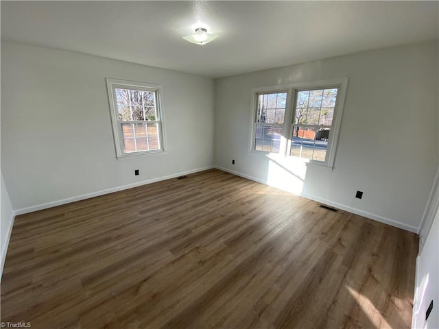 empty room with plenty of natural light and dark hardwood / wood-style flooring