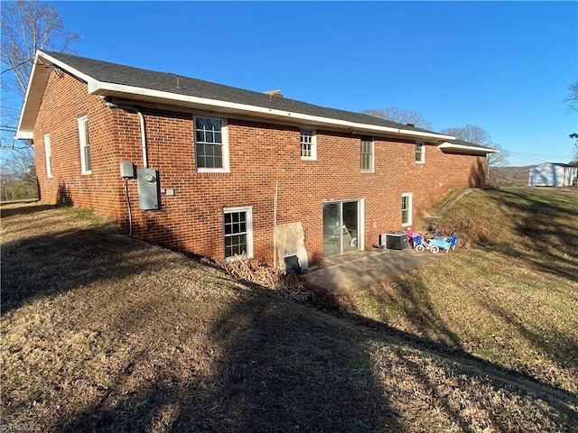 back of property with a lawn and a patio